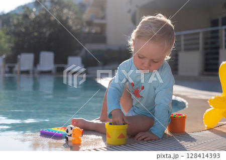Toddler Playing in a Pool Wearing a Sun Protection Shirt 128414393