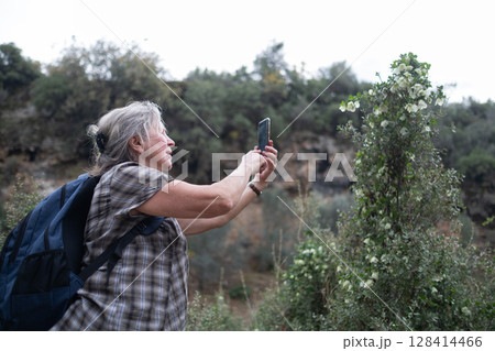 Elderly Woman Taking Photos During a Hike Elderly Woman Taking Photos During a Hike 128414466