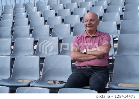 Elderly Man Sitting in an Empty Stadium, Feeling Content 128414475