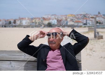 Elderly Man Sitting on Bench on Beach and Relaxing during Vacation in Portugal 128414537