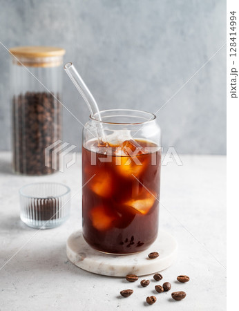 Cold brew coffee in a glass with ice on a light background with coffee beans. Cold brew coffee in a glass with ice on a light background with coffee beans. 128414994