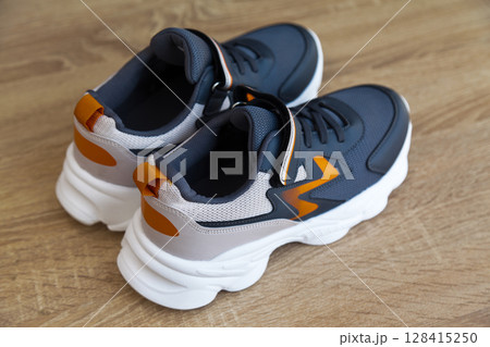 Stylish comfortable and useful grey or blue orange sneakers, on oak wooden floor Stylish comfortable and useful grey or blue orange sneakers, on oak wooden floor 128415250