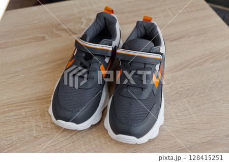 Stylish comfortable and useful grey or blue orange sneakers, on oak wooden floor Stylish comfortable and useful grey or blue orange sneakers, on oak wooden floor 128415251