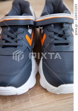Stylish comfortable and useful grey or blue orange sneakers, on oak wooden floor Stylish comfortable and useful grey or blue orange sneakers, on oak wooden floor 128415263