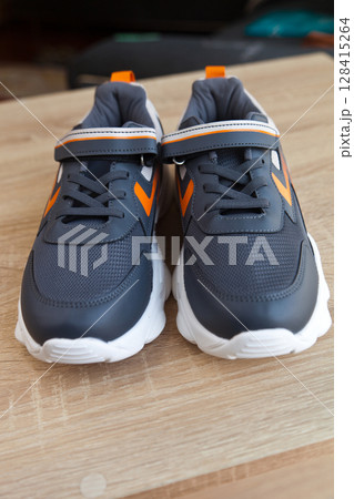 Stylish comfortable and useful grey or blue orange sneakers, on oak wooden floor Stylish comfortable and useful grey or blue orange sneakers, on oak wooden floor 128415264