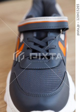 Stylish comfortable and useful grey or blue orange sneakers, on oak wooden floor Stylish comfortable and useful grey or blue orange sneakers, on oak wooden floor 128415265
