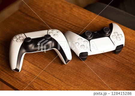 Sony PS5 Wireless Controller, on an oak wooden table, PlayStation is a video gaming brand that consists of five home video game consoles. Istanbul Turkey May 01 2025 128415286