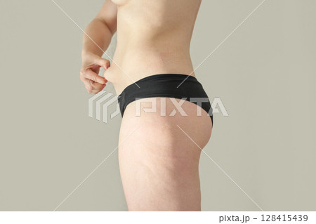Young caucasian female pinching skin on waist in black underwear showing body Young caucasian female pinching skin on waist in black underwear showing body 128415439