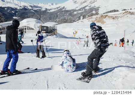 Snowboarders and skiers ski in the resort on the slopes 128415494