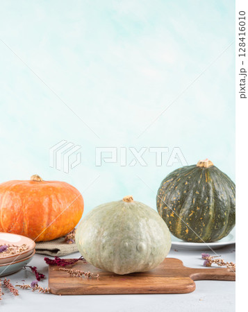 Three beautiful autumn pumpkins on gray and turquoise background 128416010