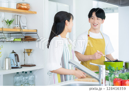 キッチンで料理を作る若い夫婦 キッチンで料理を作る若い夫婦 128416359