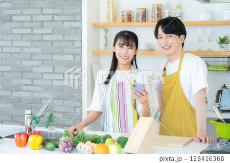 キッチンで料理を作る若い夫婦 キッチンで料理を作る若い夫婦 128416368