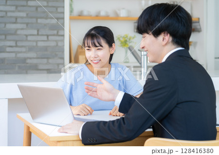 リビングで女性と商談をするビジネスマン リビングで女性と商談をするビジネスマン 128416380