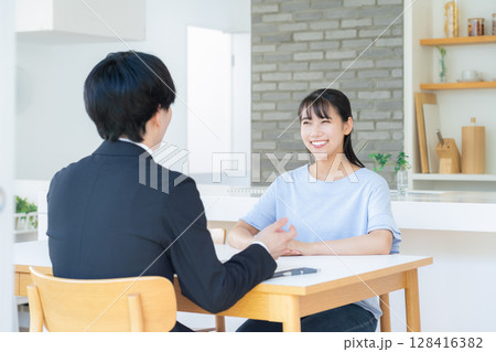 リビングで女性と商談をするビジネスマン リビングで女性と商談をするビジネスマン 128416382