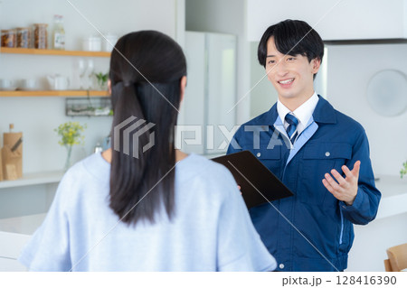 リビングで女性に説明をする不動産業者 128416390