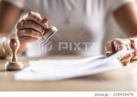 The notary office assistant stamps the archived document. Concept of official permission at the office, post office, at the notary at the court or other institution 128416470