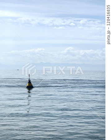 buoy floating calmly in serene ocean waters under clear sky near coast at midday. closeup. 128416835