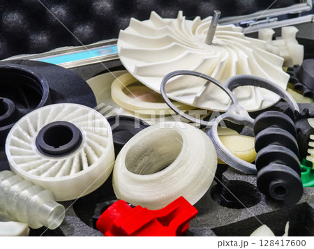 Colorful 3D printed gears and components displayed on a table at an exhibition for innovative manufacturing technologies 128417600