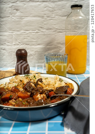 Hearty beef stew with rice and orange juice Hearty beef stew with rice and orange juice 128417653