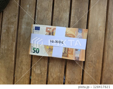 Euro currency bundle on wooden tabletop for financial concept and investment themes. Horizontal banner. Copy space. Money on a wooden background Euro currency bundle on wooden tabletop for financial concept and investment themes. Horizontal banner. Copy space. Money on a wooden background 128417821