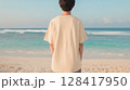 夕暮れの海辺でベージュTシャツを着た若い男性の後ろ姿 | 柔らかい印象 128417950