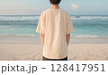 夕暮れの海辺でベージュTシャツを着た若い男性の後ろ姿 | 柔らかい印象 128417951