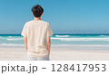 青い海を見つめるベージュTシャツの若い男性 | 後ろ姿 128417953