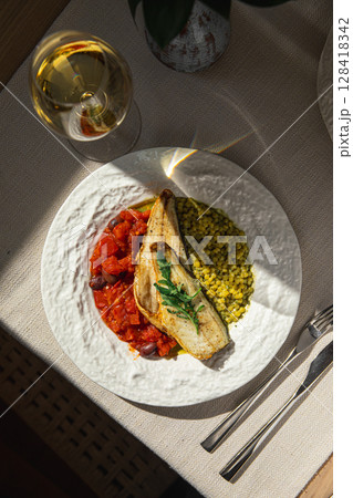 Portion of sea bass fillet with ptitim and tomato Portion of sea bass fillet with ptitim and tomato 128418342