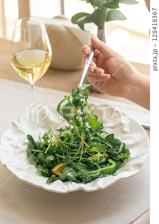 Woman eating green salad with avocado and arugula 128418367