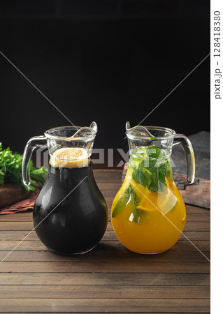Kvass and lemonade in glass jugs on wooden table Kvass and lemonade in glass jugs on wooden table 128418380