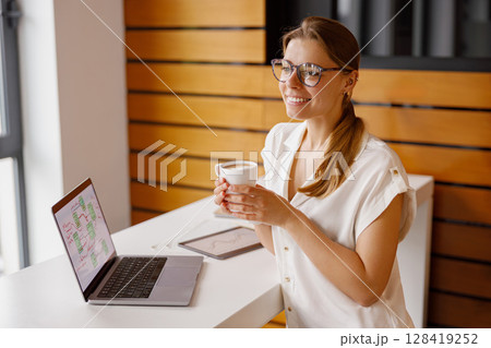 A Cheerful and Professional Individual Engaged in Work Within a Modern Office Environment 128419252