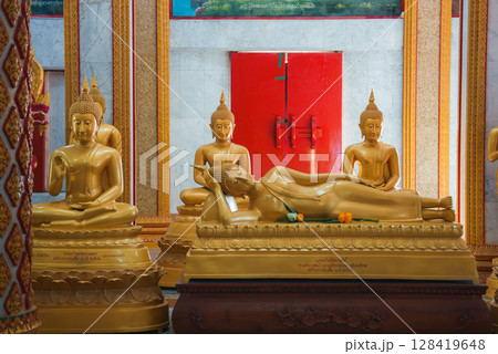 Serene temple interior in Thailand featuring a reclining Buddha statue, surrounded by seated Buddhas on ornate pedestals with vibrant red and gold decor. Serene temple interior in Thailand featuring a reclining Buddha statue, surrounded by seated Buddhas on ornate pedestals with vibrant red and gold decor. 128419648