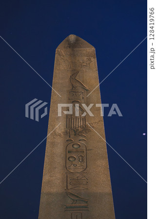 The Obelisk of Theodosius in Istanbul, Turkey, features intricate hieroglyphic carvings illuminated at night, standing out against a dark blue sky. The Obelisk of Theodosius in Istanbul, Turkey, features intricate hieroglyphic carvings illuminated at night, standing out against a dark blue sky. 128419766