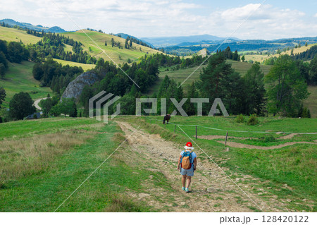 Senior Woman Walking on Forest Trail with Backpack 128420122