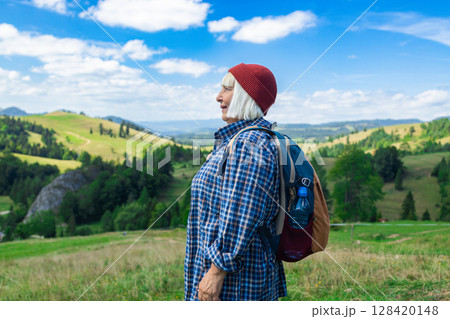 Senior woman enjoying scenic mountain landscape during hike Senior woman enjoying scenic mountain landscape during hike 128420148
