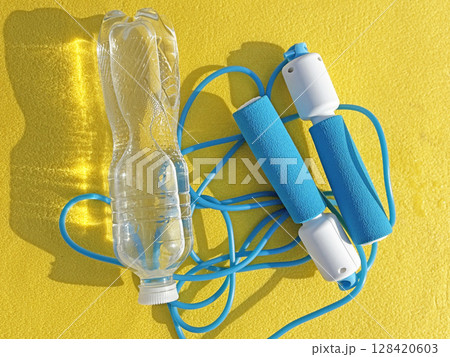Jump rope and water bottle on sports mat, top view. Fitness and workout gear, healthy lifestyle concept	 128420603