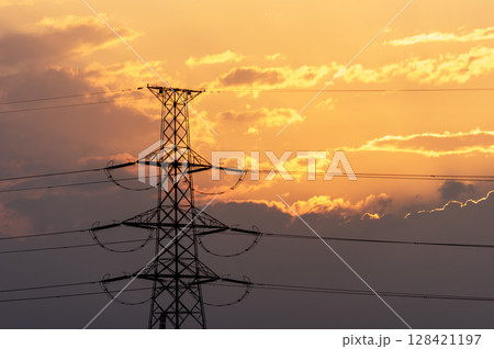 オレンジ色の夕焼け空と送電鉄塔のシルエット オレンジ色の夕焼け空と送電鉄塔のシルエット 128421197
