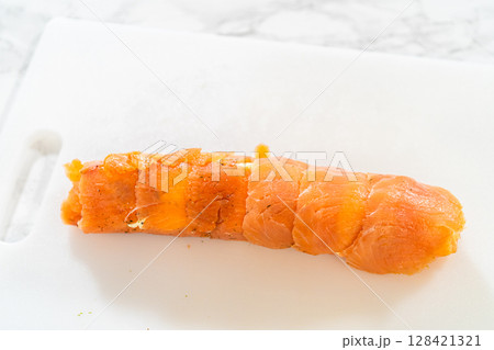 A fully rolled smoked salmon jumbo roll, showcasing the neat and compact structure of the appetizer. 128421321