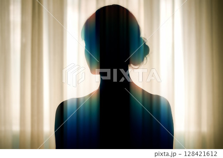 Contemplative silhouette of woman standing in front of window with artistic light effect, concept for introspection and mental health awareness 128421612