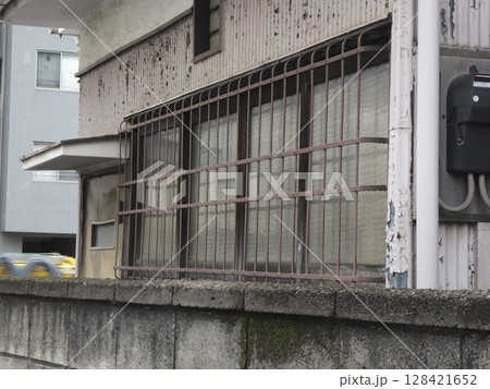 窓格子のある古い建物と、かすかに見える電車 128421652