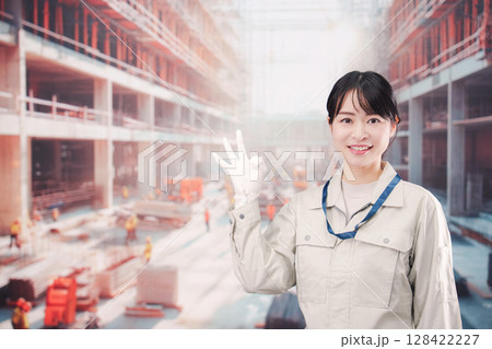 ビルの建築現場で働く作業着を着た若い女性 128422227