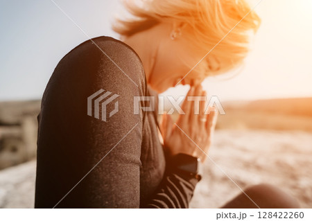 Woman in Black Clothing Meditating on a Mountaintop 128422260
