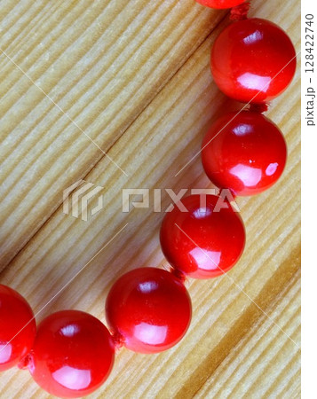 Shiny red coral beads on wooden background. Close-up. Shiny red coral beads on wooden background. Close-up. 128422740