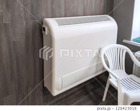 Aesthetic modern room design with split system on brown wooden wall, white plastic chair 128423018