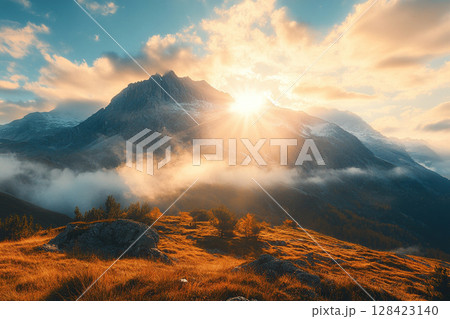 View of sunset over the mountains. The setting sun casts a warm golden light, blue cloudy sky. 128423140