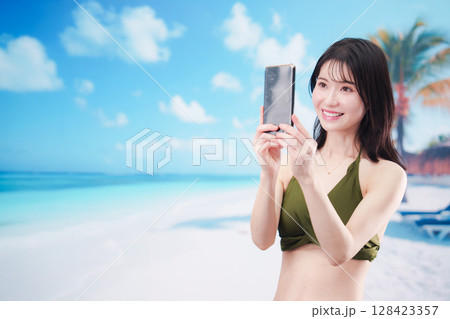 快晴のビーチでスマホで自撮りをする水着を着た若い女性 快晴のビーチでスマホで自撮りをする水着を着た若い女性 128423357