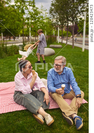 Grandparents with kids at summer park picnic on green grass 128423473