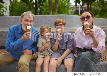 Timeless taste. Grandparents and children eating ice cream together outdoors 128423550