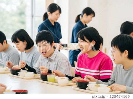 障がい者施設で食事を配膳する笑顔の女性介護士 配膳、ランチタイム、給食、食事、楽しみ 128424169