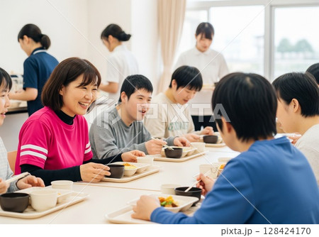 障がい者施設で食事を配膳する笑顔の女性介護士 配膳、ランチタイム、給食、食事、楽しみ 128424170